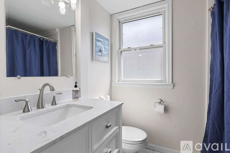 A bathroom with a sink, toilet, and a window.