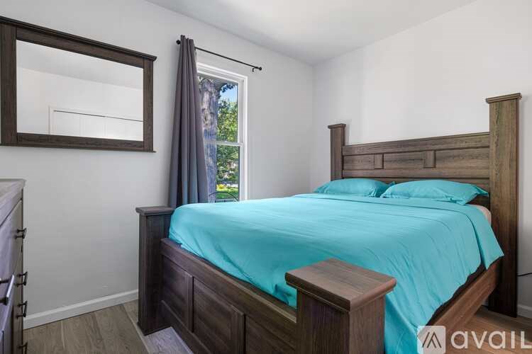 A bedroom with a bed, wooden headboard, and a window with curtains.