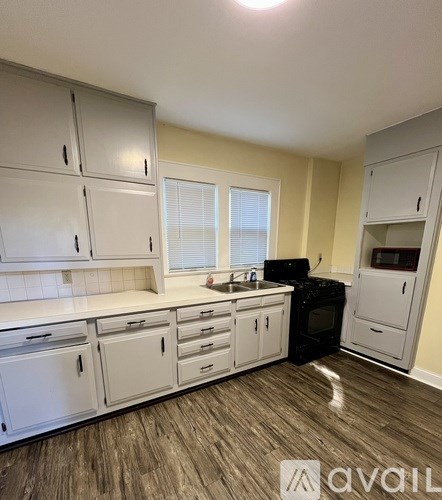 A kitchen with white cabinets and a black oven.