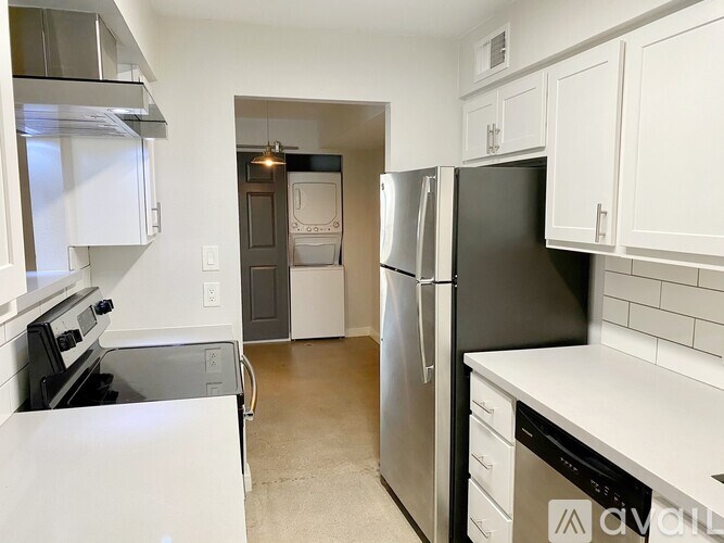 A kitchen with white cabinets and a black fridge.