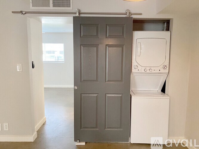 A white fridge is in a room with a grey door.
