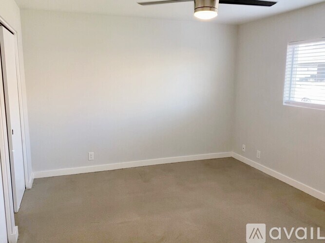 A room with a ceiling fan and a window with blinds.