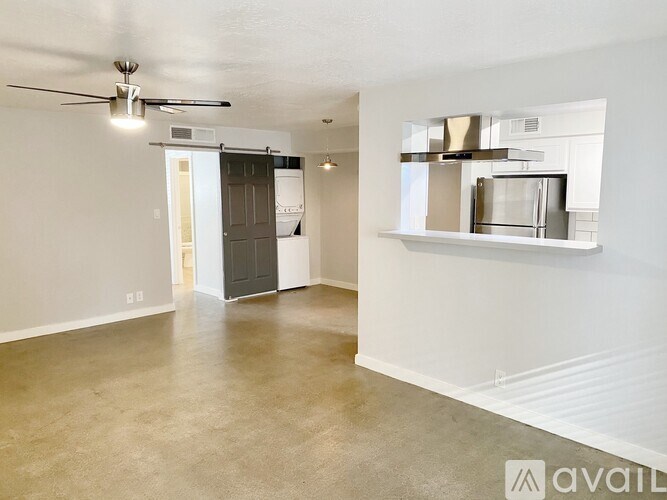 A room with a ceiling fan and a microwave on a shelf.