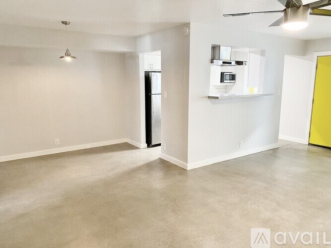 A spacious room with a ceiling fan and a refrigerator.
