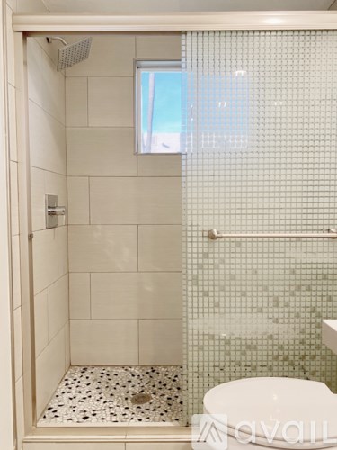 A white toilet in a small bathroom with a shower.