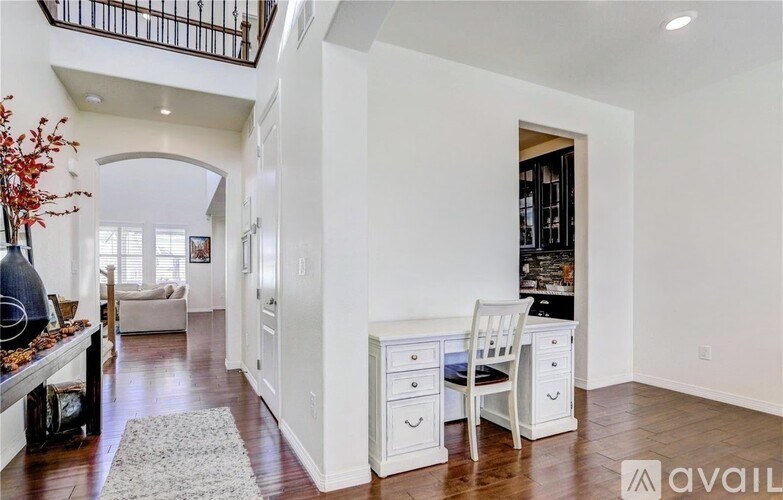 A white desk with a chair is in a room with a white wall.