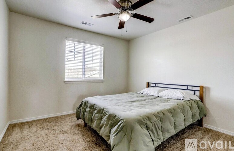 A bedroom with a bed, carpet, and a ceiling fan.