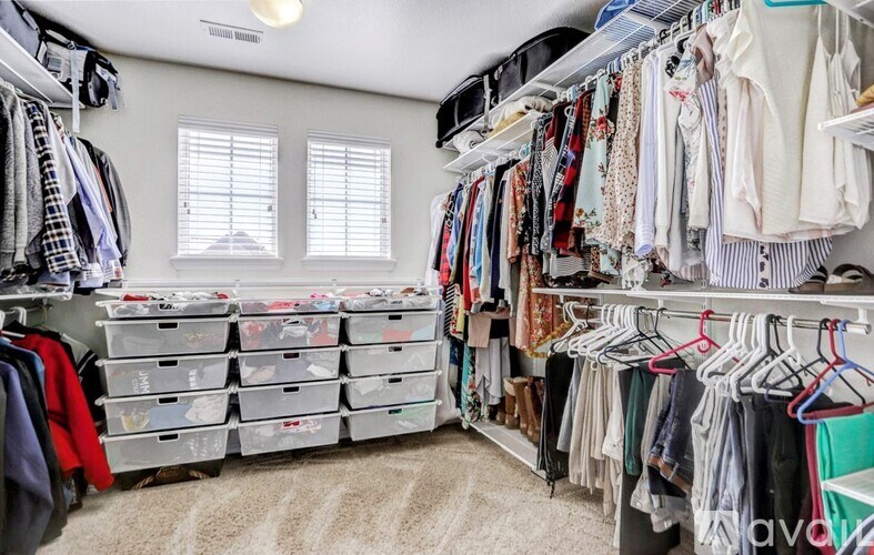A well-organized walk-in closet with clothes and drawers.