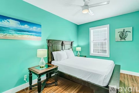 A bedroom with a bed, nightstand, and a painting of a beach scene on the wall.