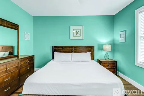 A bedroom with a bed, nightstand, and a mirror.