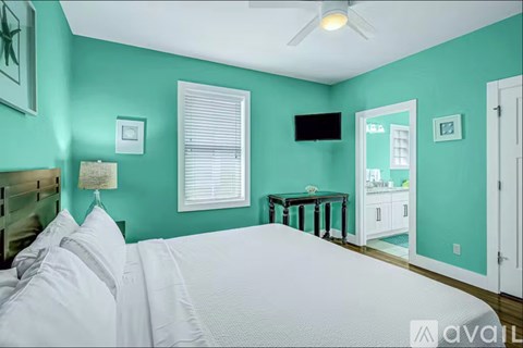 A bedroom with a bed, a table, a television, and a window.