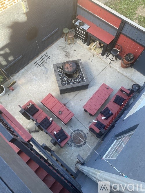 A red and black table is surrounded by red chairs on a patio.