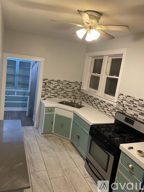 A kitchen with a stove top oven and a fan.