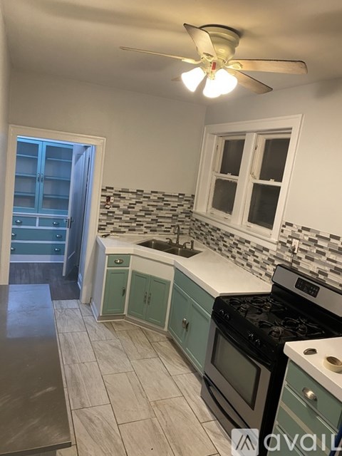A kitchen with a stove top oven and a fan.