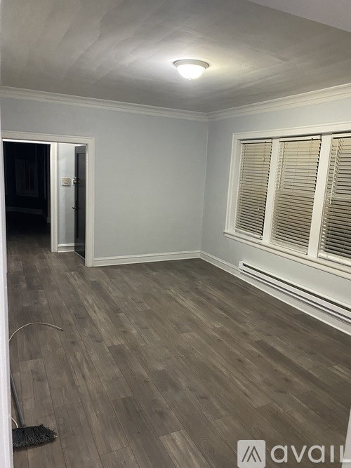 A room with wooden flooring and a window with blinds.