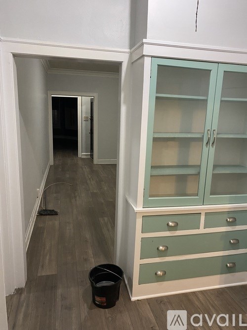 A room with a cabinet and a trash can.