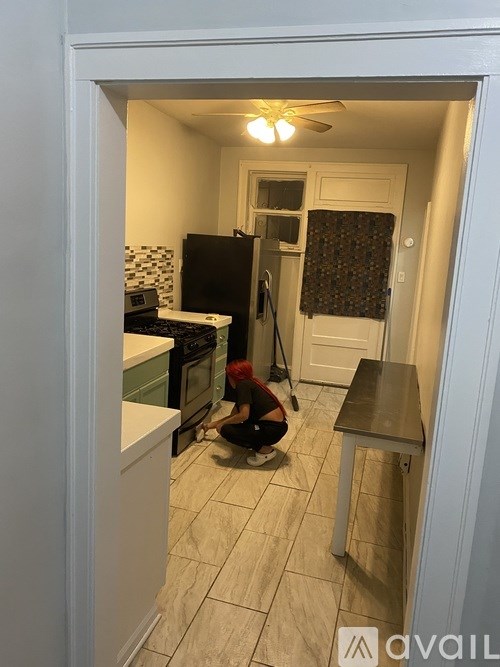 A woman is cleaning the floor of a kitchen.