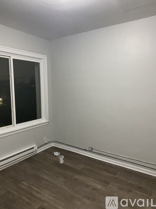 A room with a window and a wooden floor.