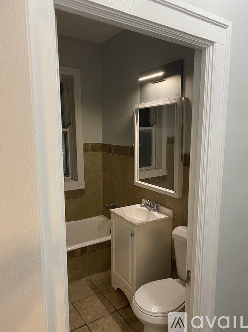 A bathroom with a toilet, sink, and mirror.
