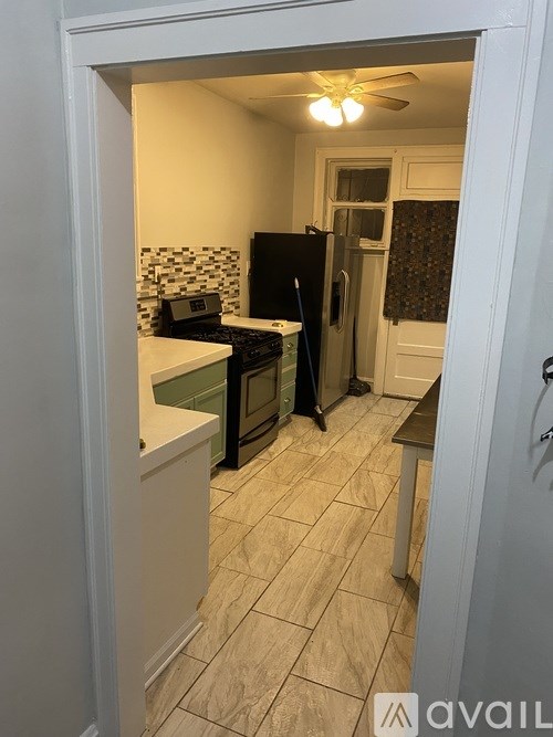A kitchen with a black fridge and a black and white tiled backsplash.