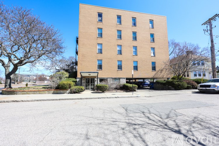 A tall building with many windows is surrounded by a parking lot.