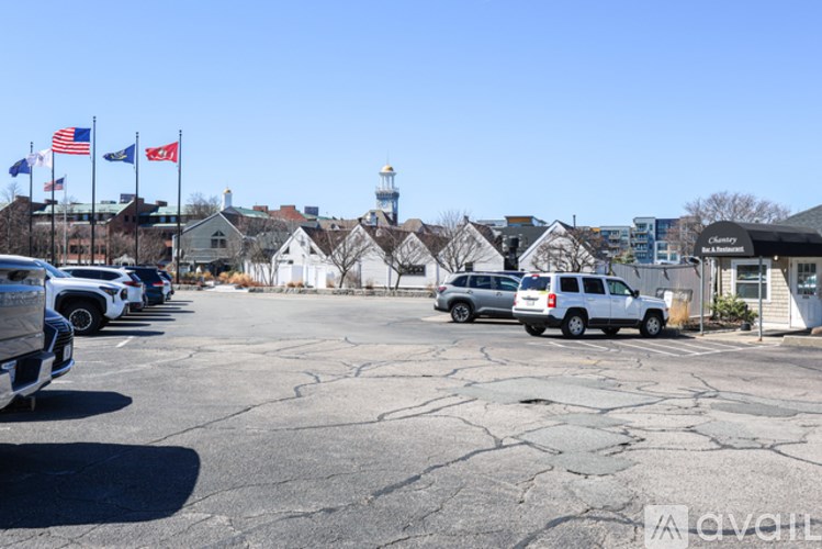 A parking lot with cars and a lighthouse in the background.