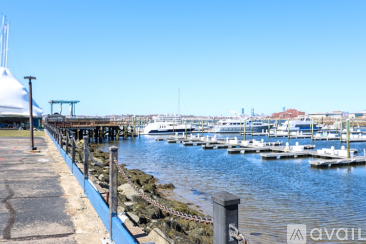 A dock with boats in the background and a pier with a white building on the left.