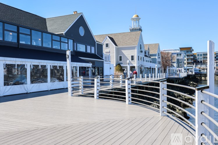 A wooden deck with a railing and a building with a tower in the background.