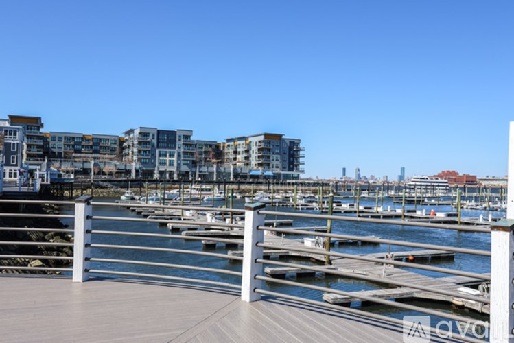 A dock with a metal railing in front of a body of water with boats.