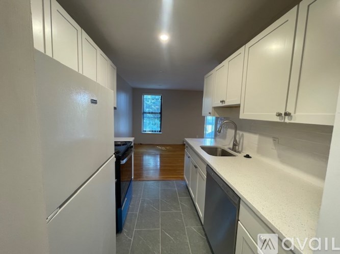 A kitchen with white cabinets and a window.