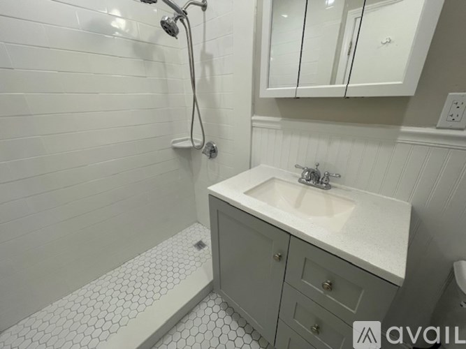 A white tiled bathroom with a sink and shower.