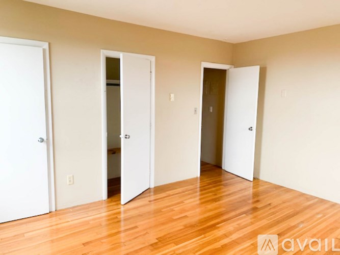 A room with three doors and wooden floors.