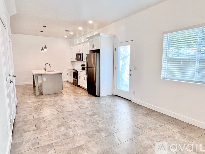 A kitchen with tile flooring and a refrigerator.