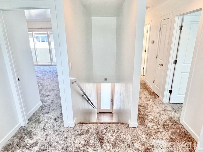 A hallway with a carpeted floor and white walls.