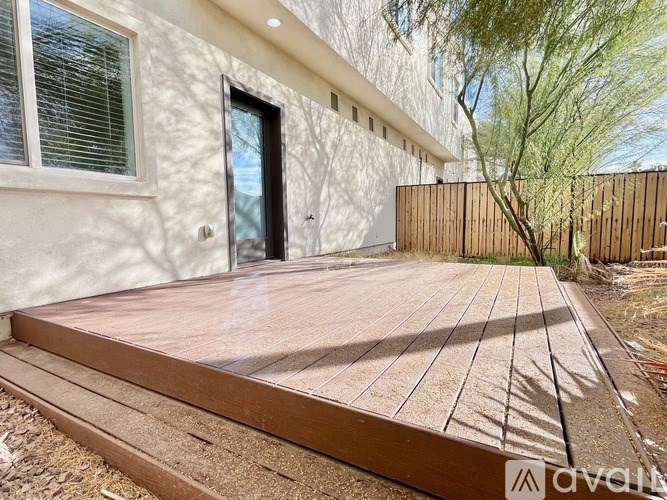 A wooden deck leads to a modern house with a black door.