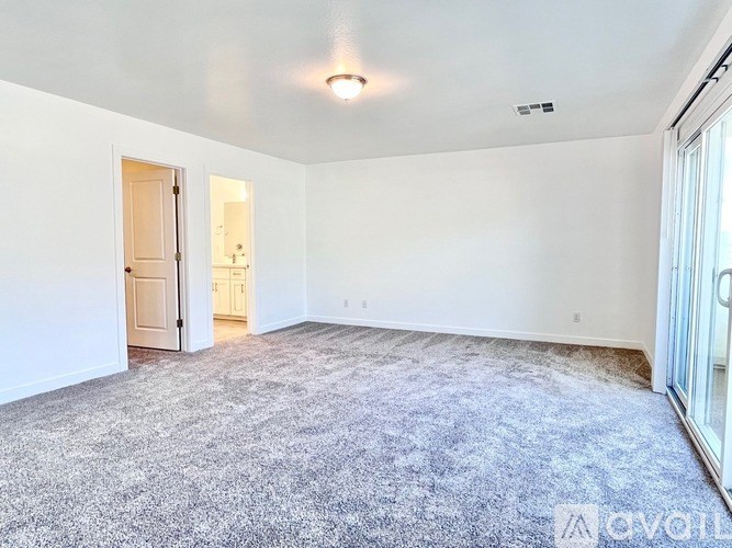 A large, empty room with a carpeted floor and white walls.