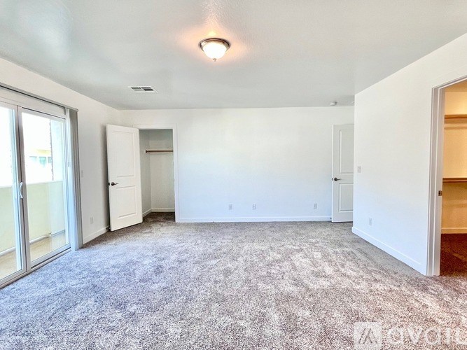 A carpeted room with a door and a window.