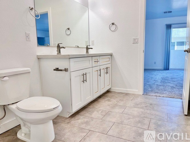 A bathroom with a toilet, sink, and cabinets.
