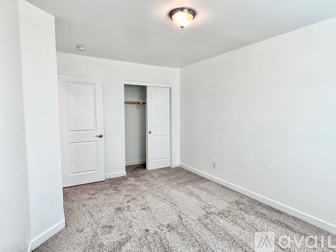 A room with a carpeted floor and two doors.