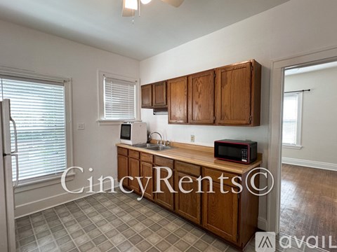 A kitchen with wooden cabinets and a microwave on the counter.
