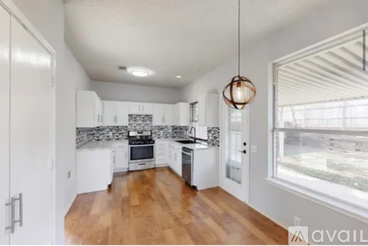 A kitchen with white cabinets and a wooden floor.