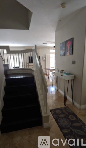 A staircase with a black carpeted runner and a white railing.