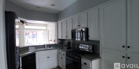 A kitchen with white cabinets and a black refrigerator.