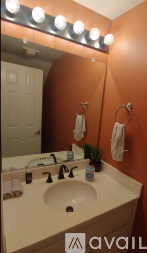 A bathroom with a sink and a mirror with lights on it.