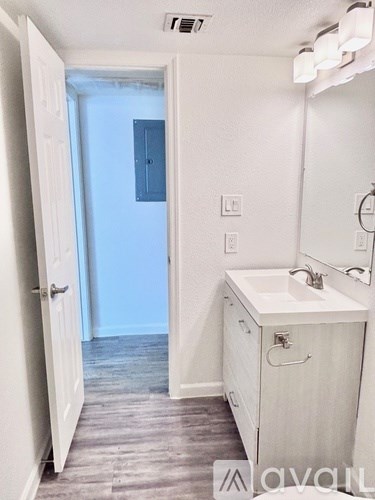 A bathroom with a sink, mirror, and wooden floors.