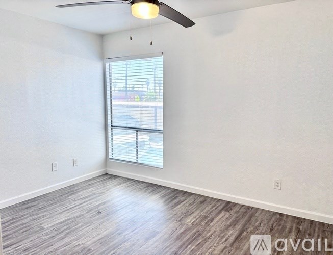 A room with a ceiling fan and a window with blinds.