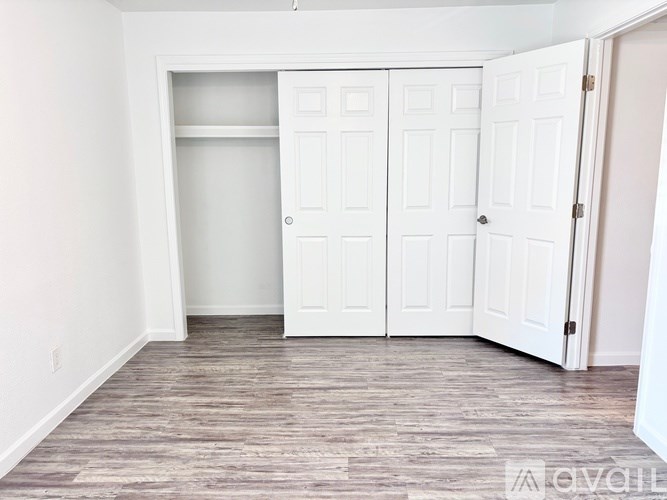 A room with white doors and wooden flooring.