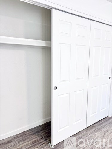 A white closet with a door open and a logo on the bottom right.