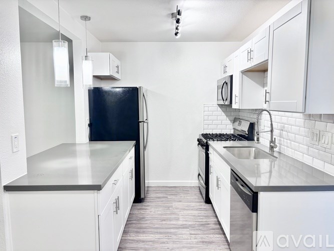 A kitchen with a black fridge and white cabinets.