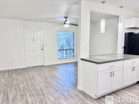 A spacious kitchen with white cabinets and a ceiling fan.
